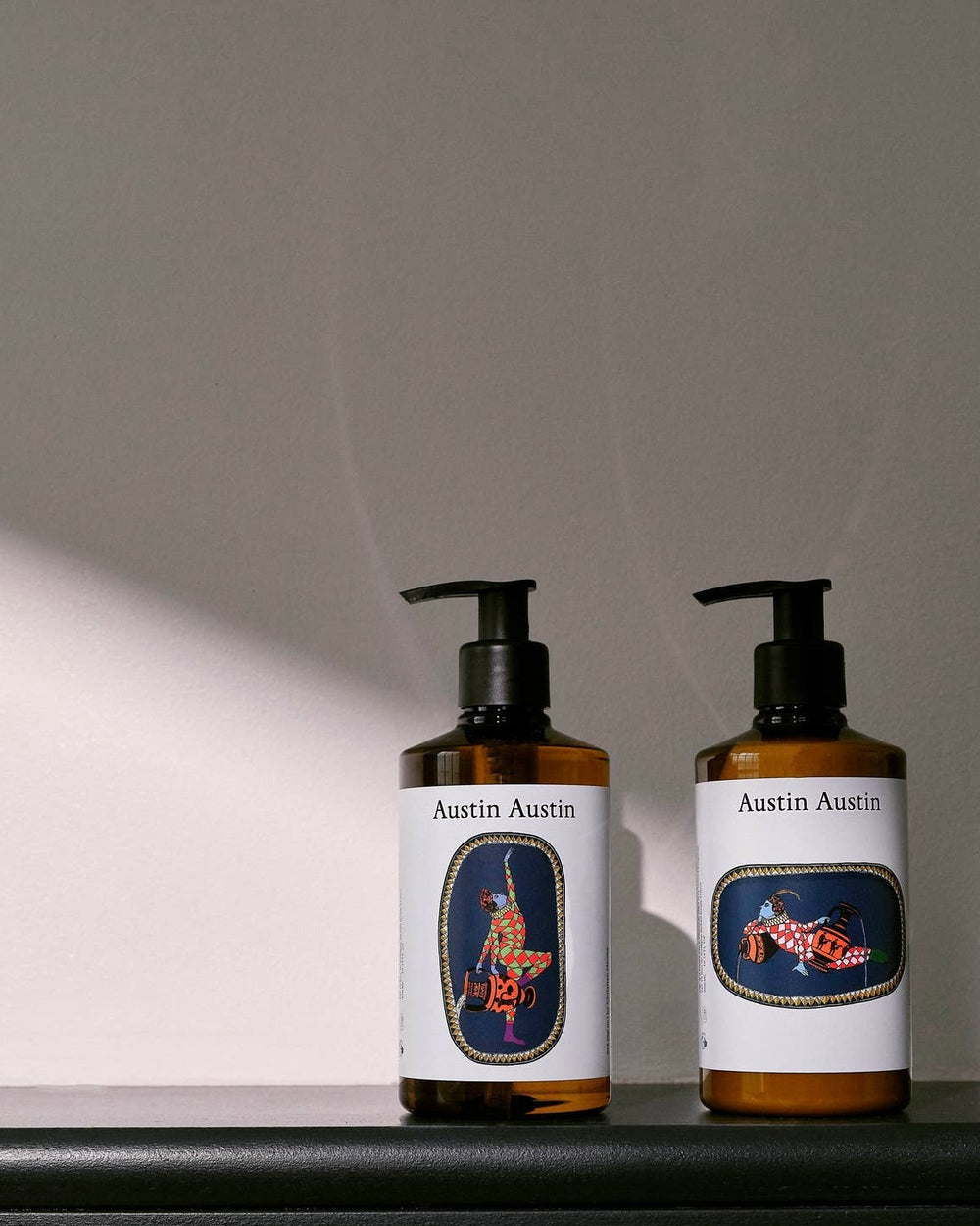 Two bottles of Austin Austin products on a gray background