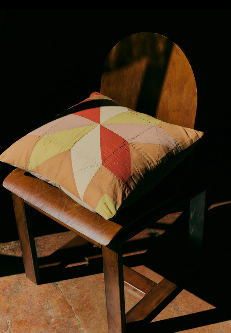 Patchwork pillow on a wooden chair with a dark background